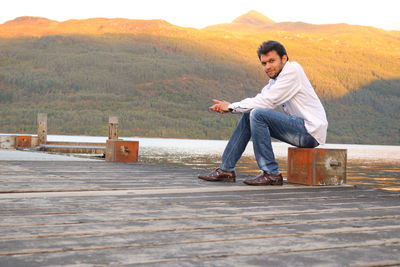 Full length of young man sitting on mountain