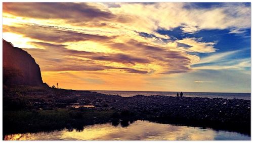 Scenic view of sea against cloudy sky during sunset