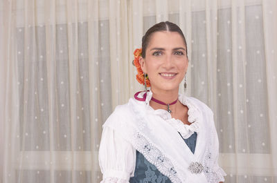 Portrait of smiling young woman standing against wall