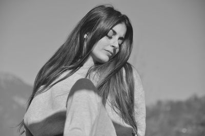 Portrait of young woman standing against sky