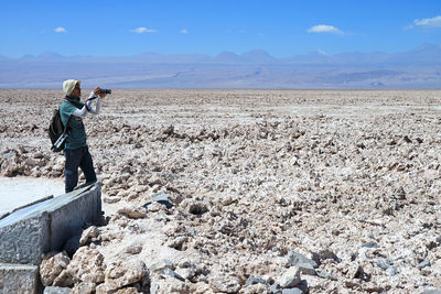 Rear view of woman walking on field against sky