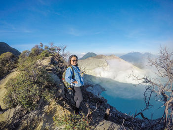 Woman wearing sunglasses standing on mountain against sky