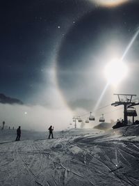 People on snowcapped mountain against sky during winter