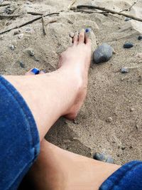 Low section of woman relaxing on sand at beach