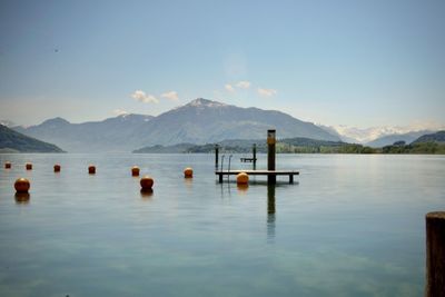 Wooden posts in lake against sky
