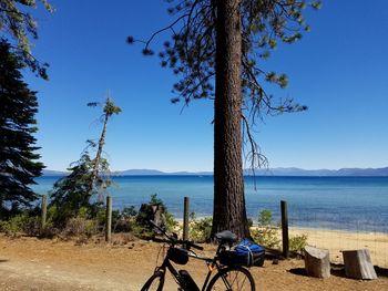 Bicycle parked at beach against sky