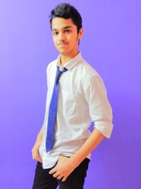 Portrait of young man standing against blue wall