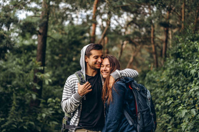 Young couple standing against trees