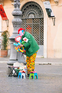 Clown holding balloons and toys on footpath