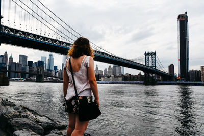 Young woman looking at the skyline of the city in manhattan bridge and east river in new york city