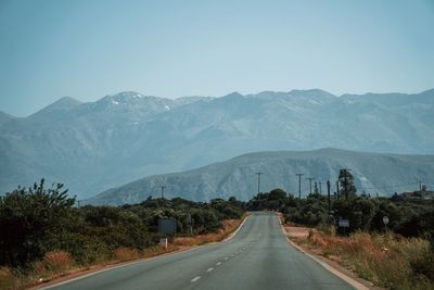 Road leading towards mountains against sky