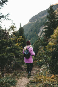 Rear view of woman standing on road amidst trees