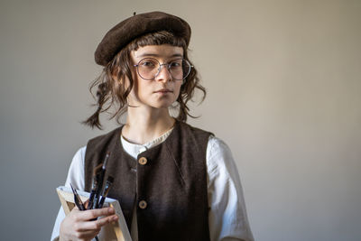 Portrait of young woman standing against wall