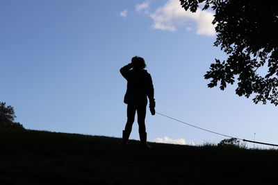 Rear view of silhouette man standing on field against sky