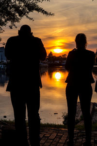 Rear view of silhouette man and woman standing during sunset