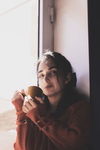 Portrait of young woman holding window