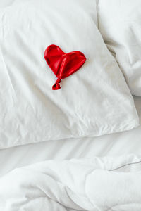 High angle view of red heart shape balloon on bed