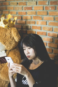 Young woman looking away while sitting on wall