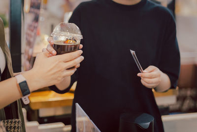 Barista serves iced coffee to customer in a coffee shop