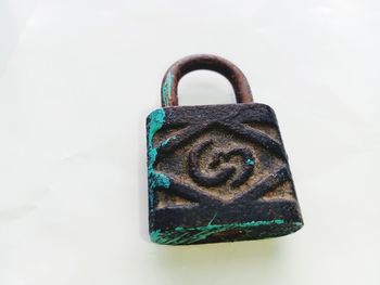 Close-up of padlocks hanging on metal against white background