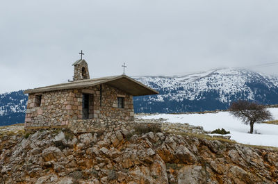 Built structure on snow covered mountain against sky