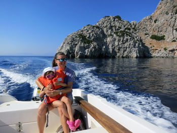 Smiling woman with daughter sitting on motorboat sailing in sea