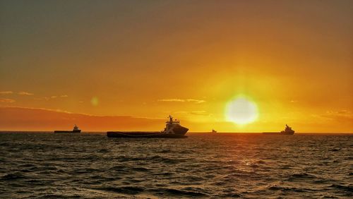 Boat sailing in sea at sunset