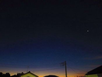 Low angle view of silhouette electricity pylon against sky at night