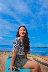 Portrait of a smiling young woman sitting on beach
