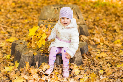Cute girl sitting on autumn leaves