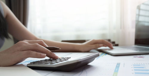 Midsection of woman using laptop on table