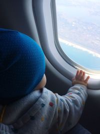 Close-up of baby boy looking through airplane window