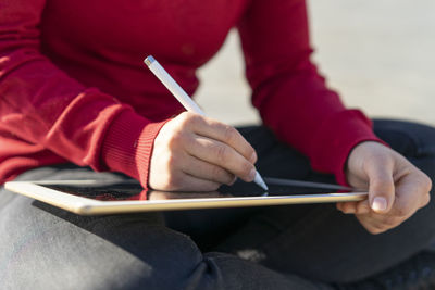 Woman working on digital tablet, using stylus, close-up