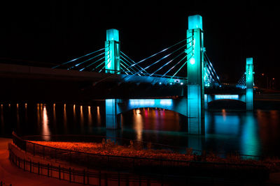 Illuminated suspension bridge over river at night