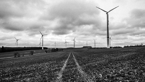 Windmills on field against sky