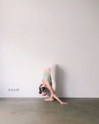 Side view of woman exercising against wall