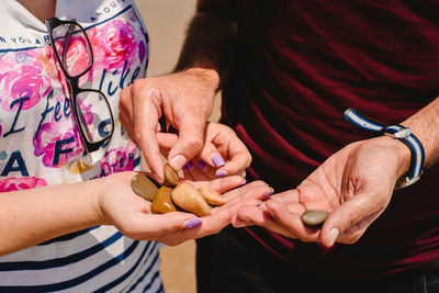 Midsection of couple holding stones