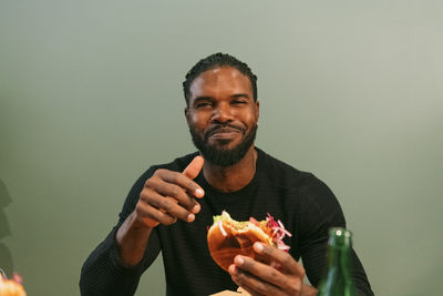 Portrait of smiling man eating burger at restaurant