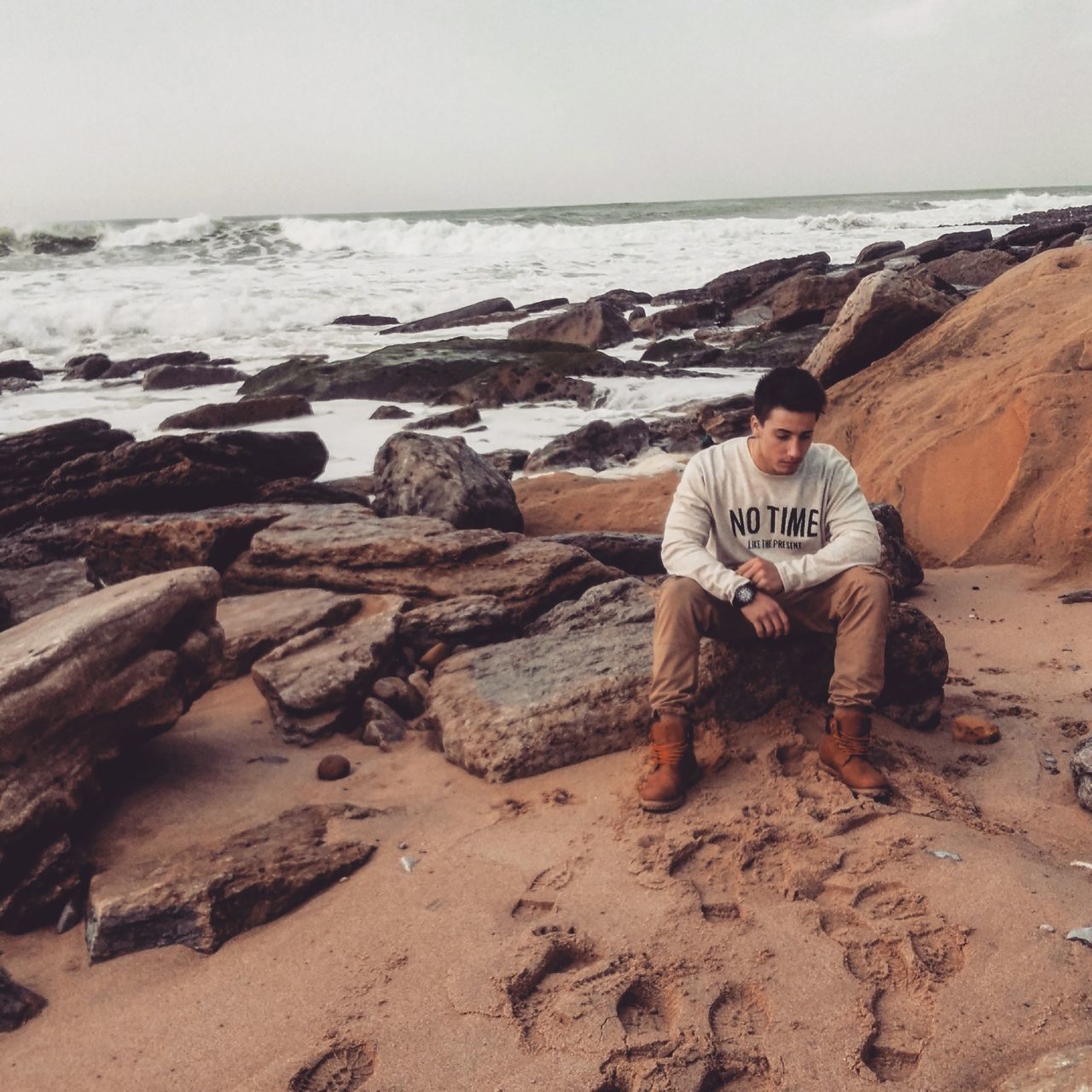 YOUNG MAN SITTING ON BEACH