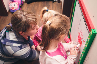 High angle view of mother with children writing on whiteboard at home