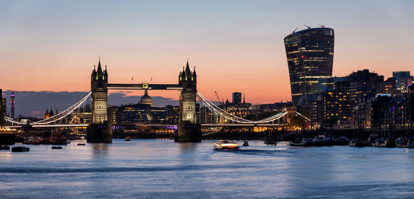 Illuminated city at waterfront during sunset