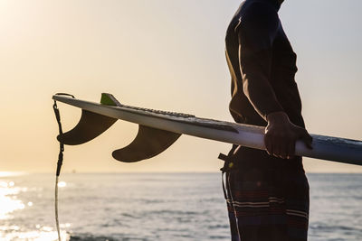 Unrecognizable surfer preparing to surf on the beach at sunrise person