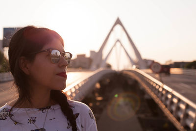 Woman in sunglasses on bridge during sunset