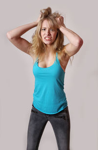 Portrait of frustrated woman standing against wall at home