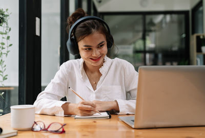 Young woman using laptop at desk in office