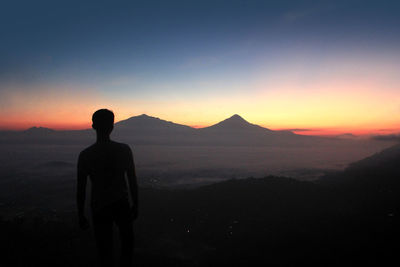 Silhouette man standing against landscape during sunset