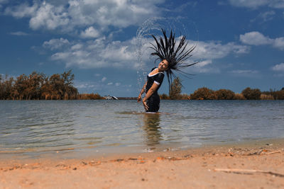 Woman standing by lake against sky