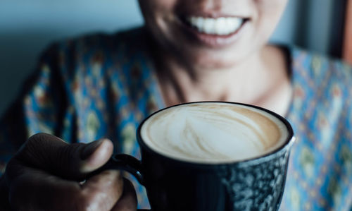 Midsection of woman holding coffee cup in cafe