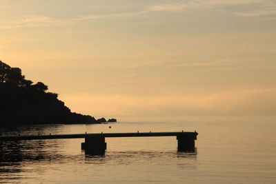 Silhouette boat in sea against sky during sunset