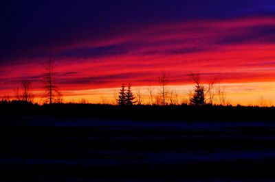 Silhouette landscape against dramatic sky during sunset